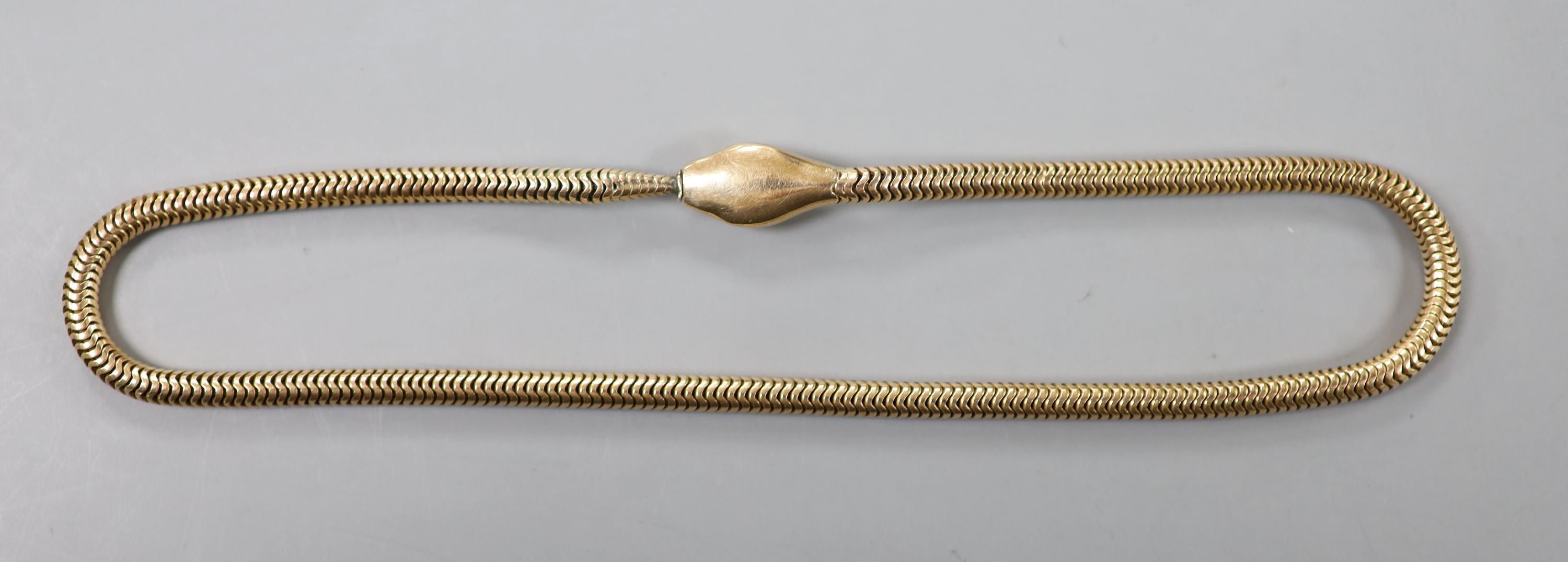 An Edwardian 9ct gold serpentine coil link serpent choker necklace, with green garnet set eyes, 36cm, gross 35 grams.
